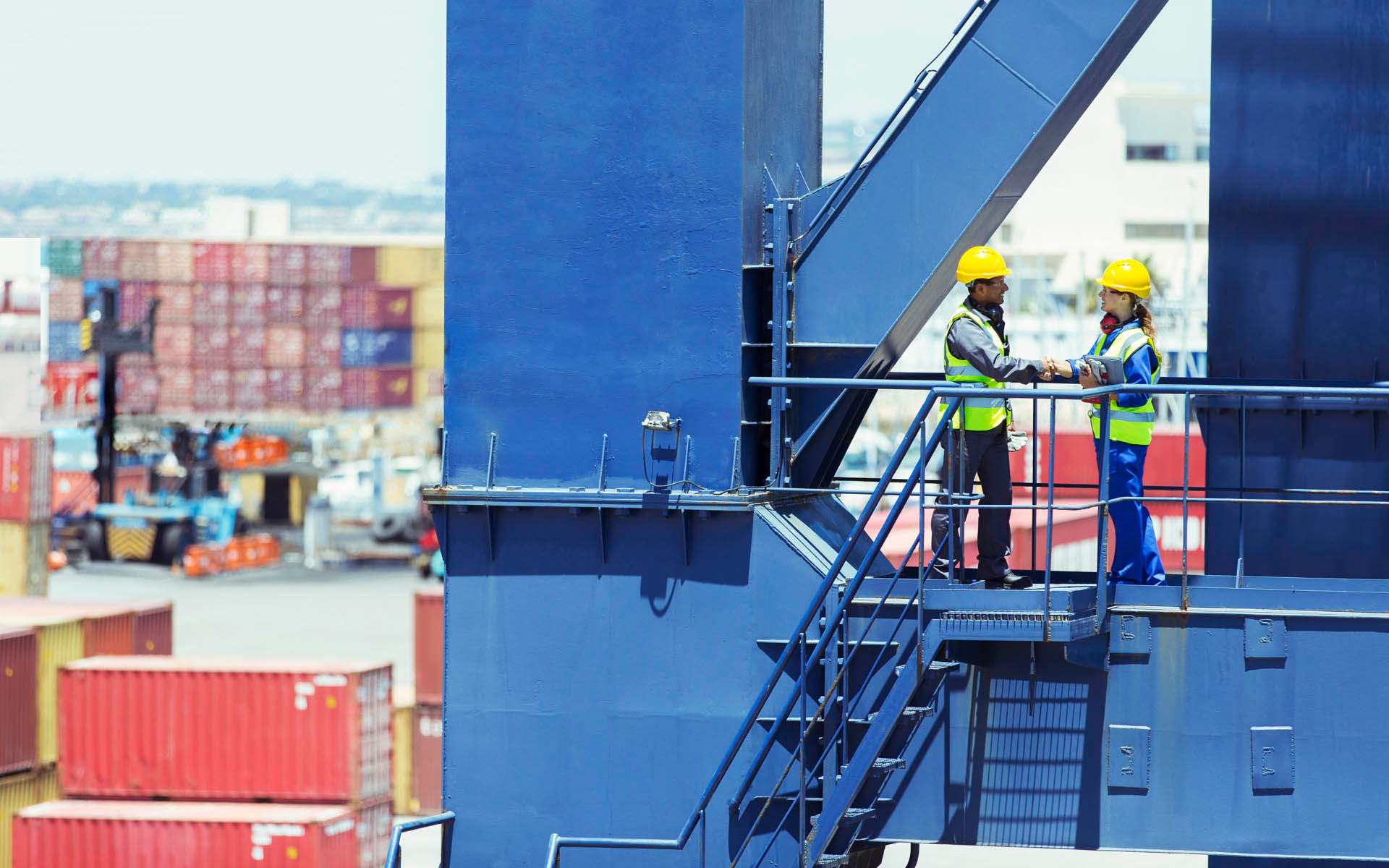 freight employees in a shipping container yard shaking hands 