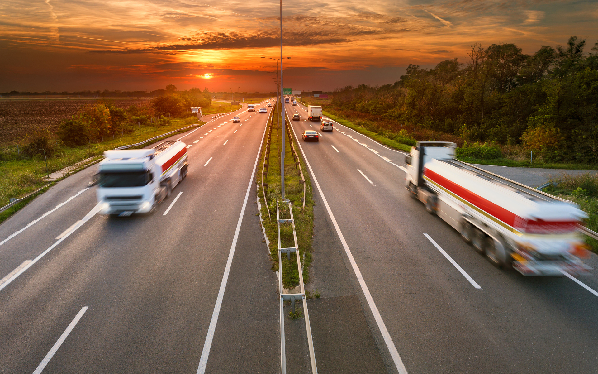 two lane interstate highway at sunset with trucks carrying goods driving by