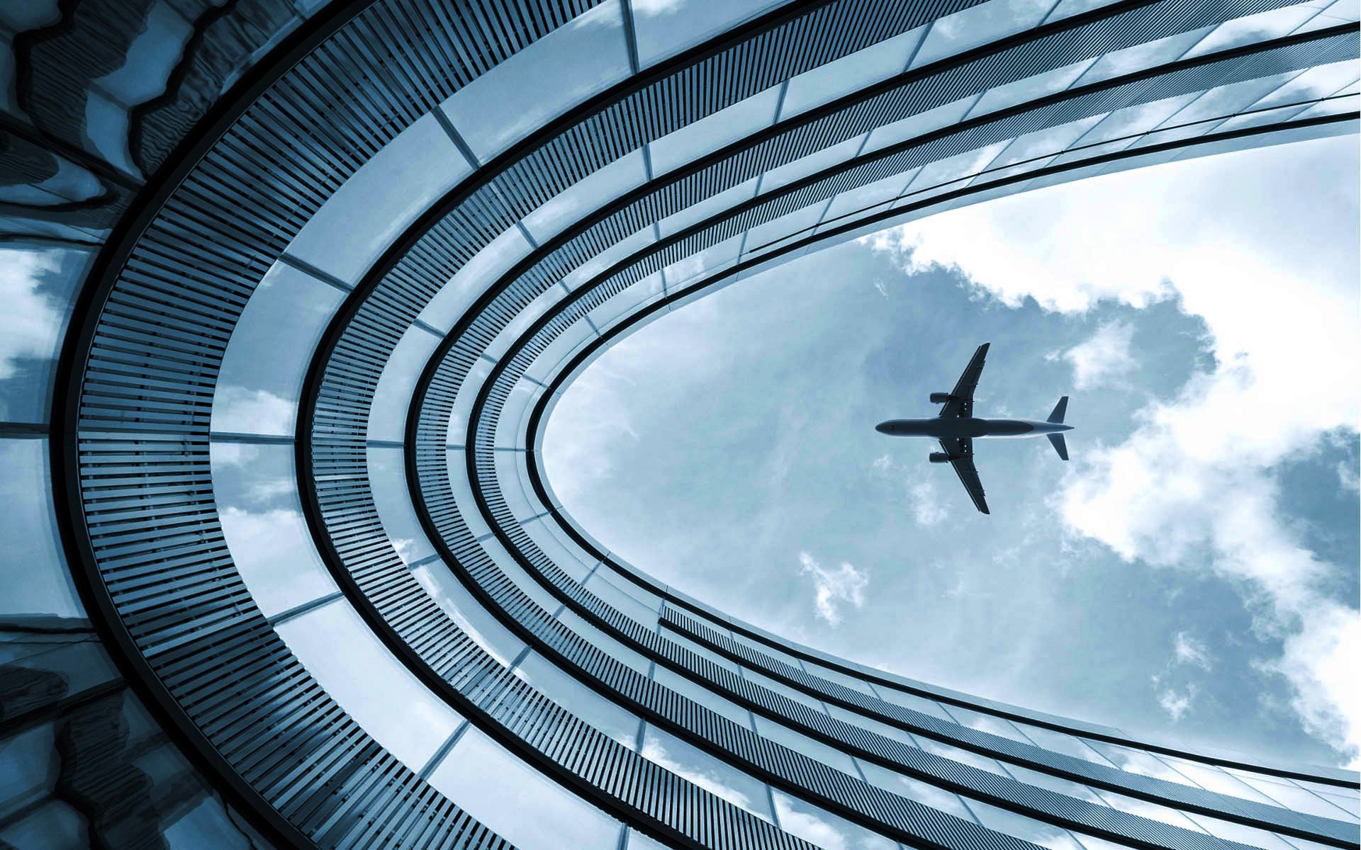 airplane flying over a glass building 