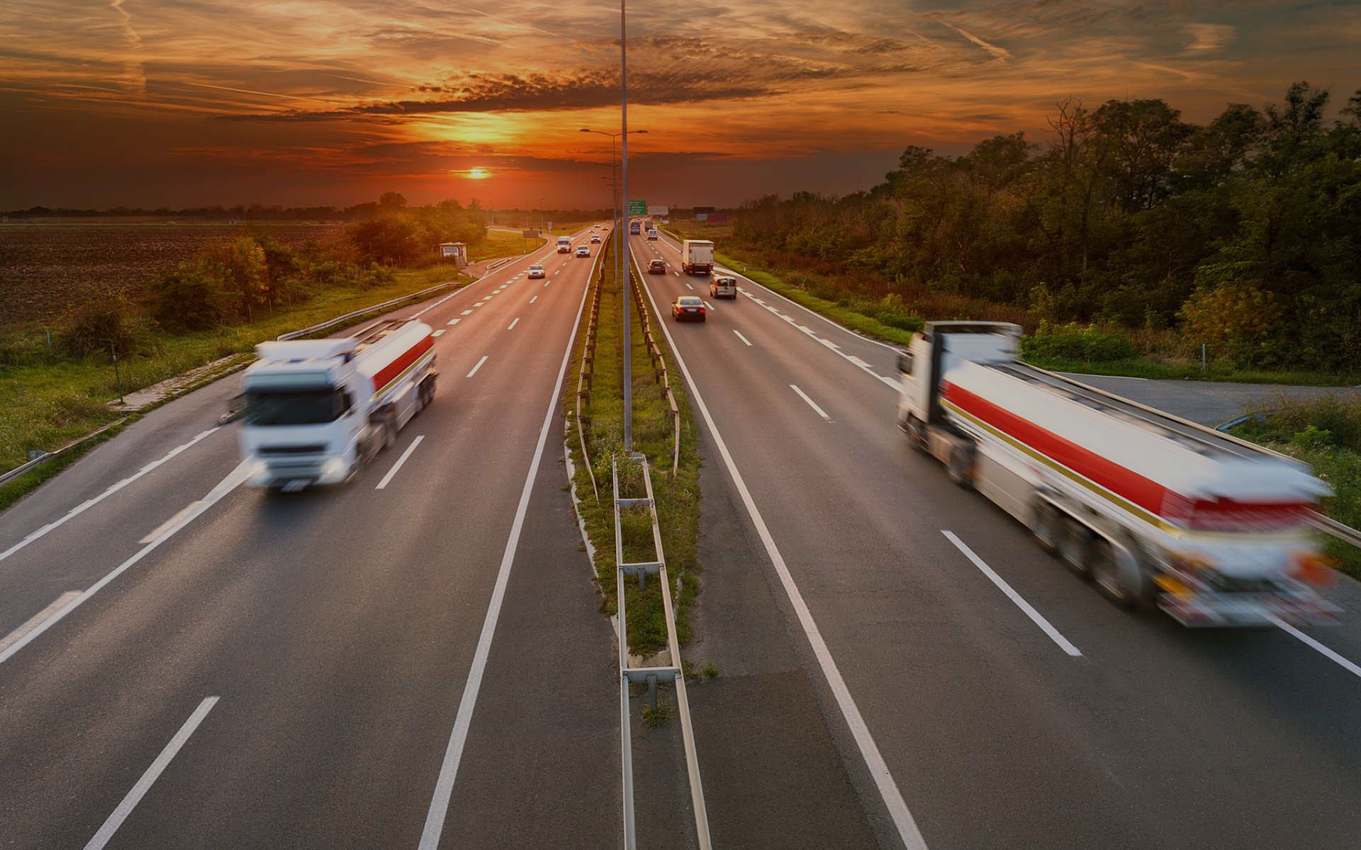 two lane interstate highway at sunset with trucks carrying goods driving by