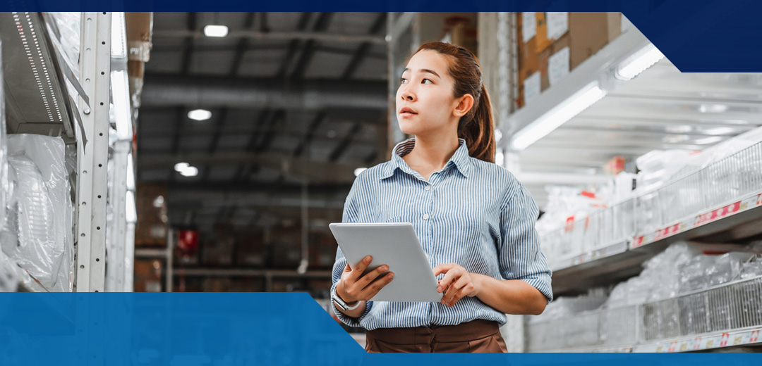 A female walks around a warehouse with a clipboard
