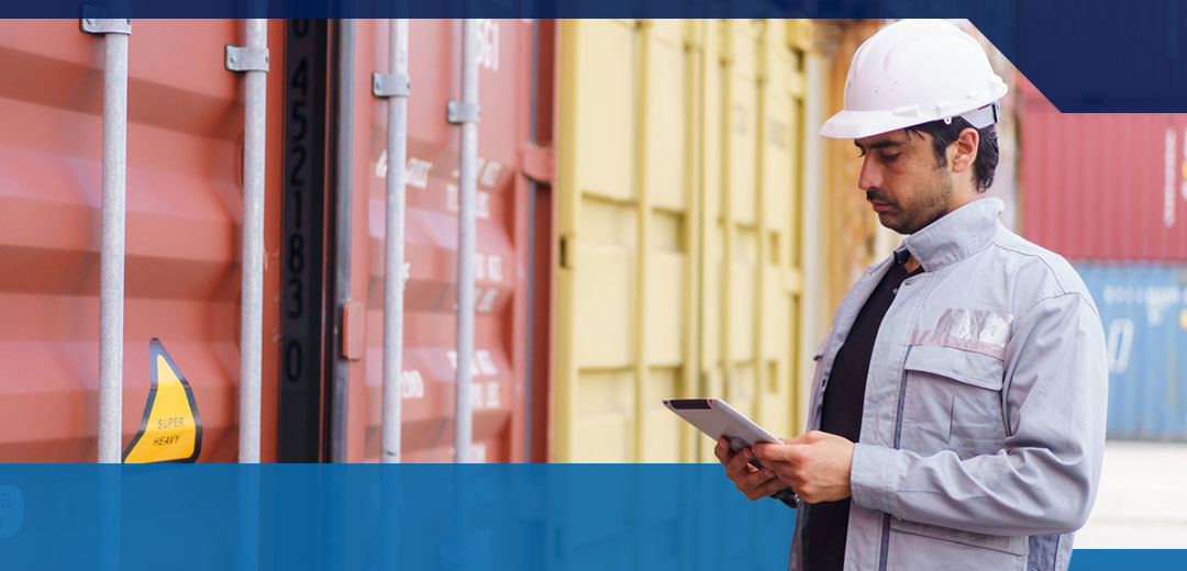 Man standing with tablet in front of shipping crates looking for a certificate of origin